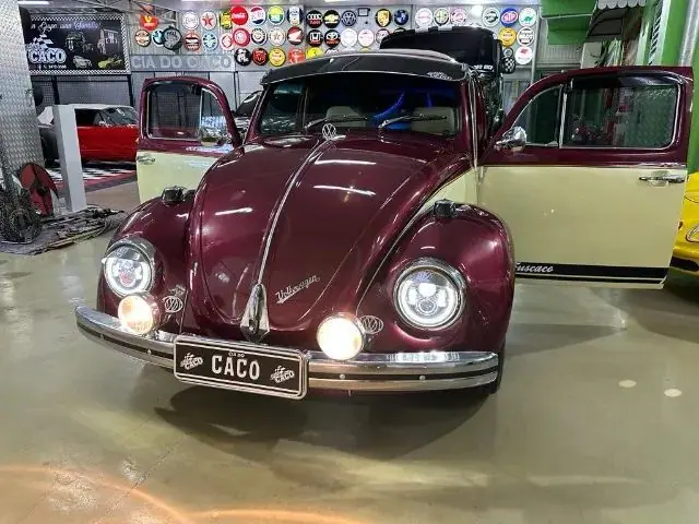 Fusca vinho e creme visto de frente, com faróis acesos
