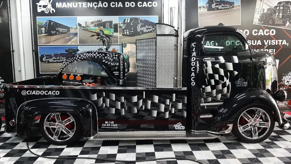 Picape preta com pintura quadriculada exposta em salão de piso quadriculado