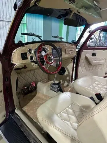 Interior do Fusca com bancos creme em matelassê e volante esportivo vermelho