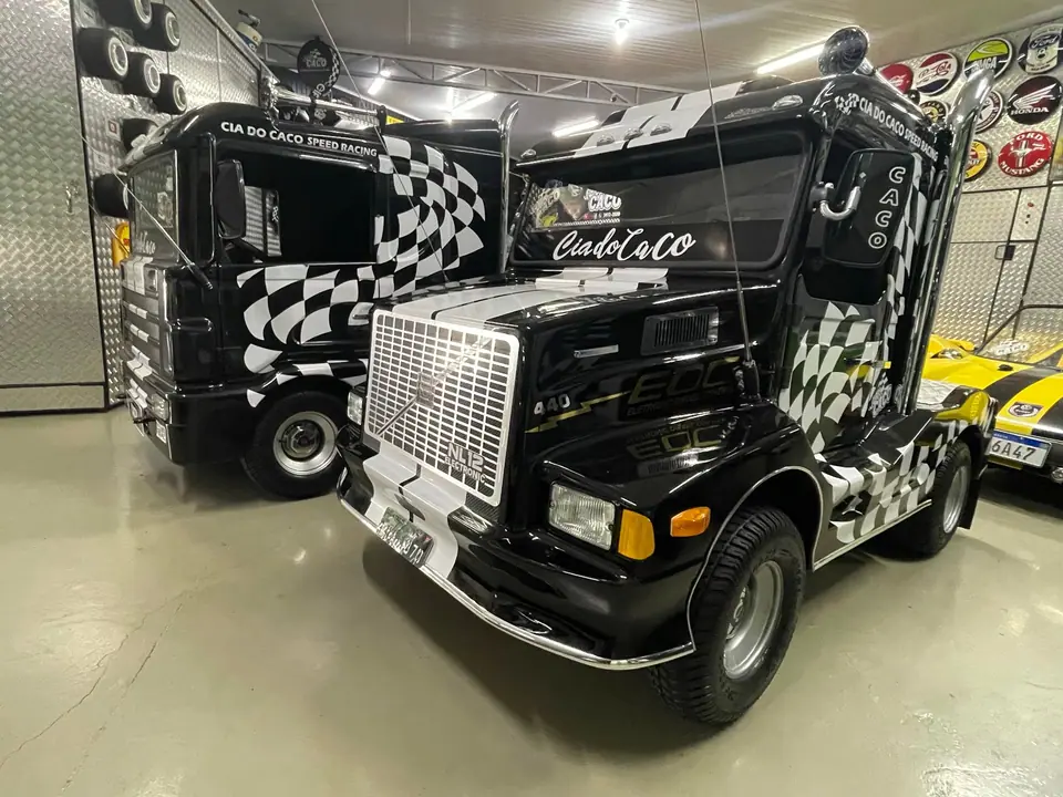 Mini caminhão preto com pintura quadriculada exposto em um galpão