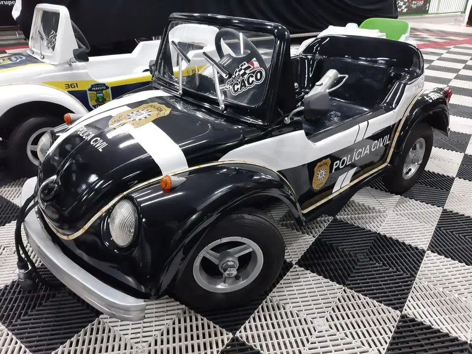 Mini carro preto com adesivos de polícia sobre piso quadriculado