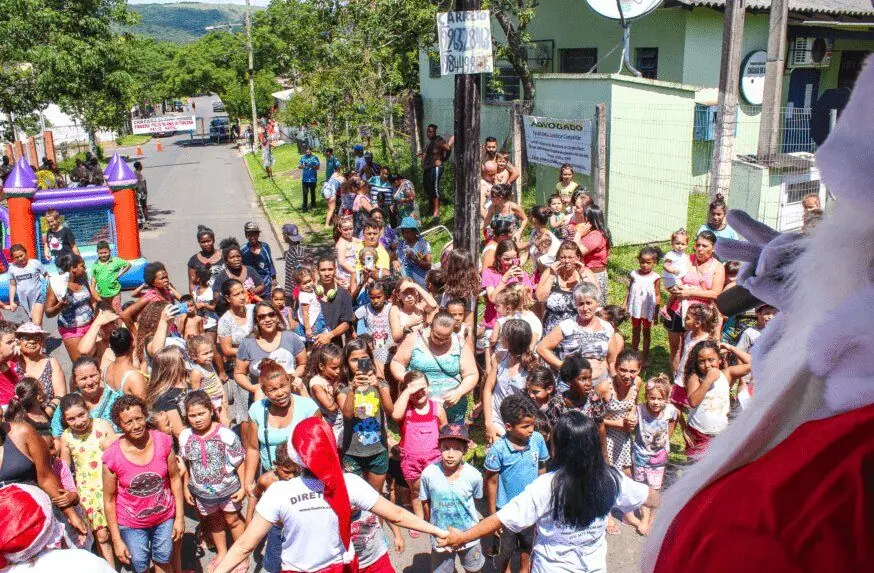 Multidão de crianças e famílias reunidas na rua durante uma entrega de Natal