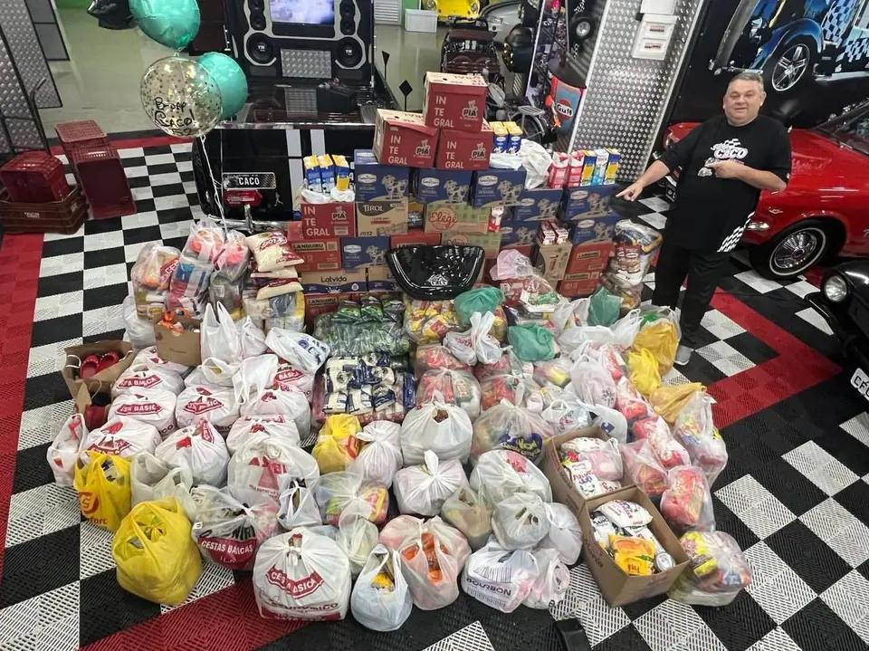 Doações de alimentos e brinquedos reunidas sobre piso quadriculado