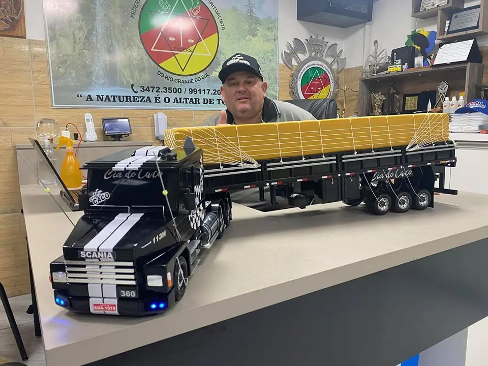 Homem ao lado de uma grande miniatura de caminhão com carreta