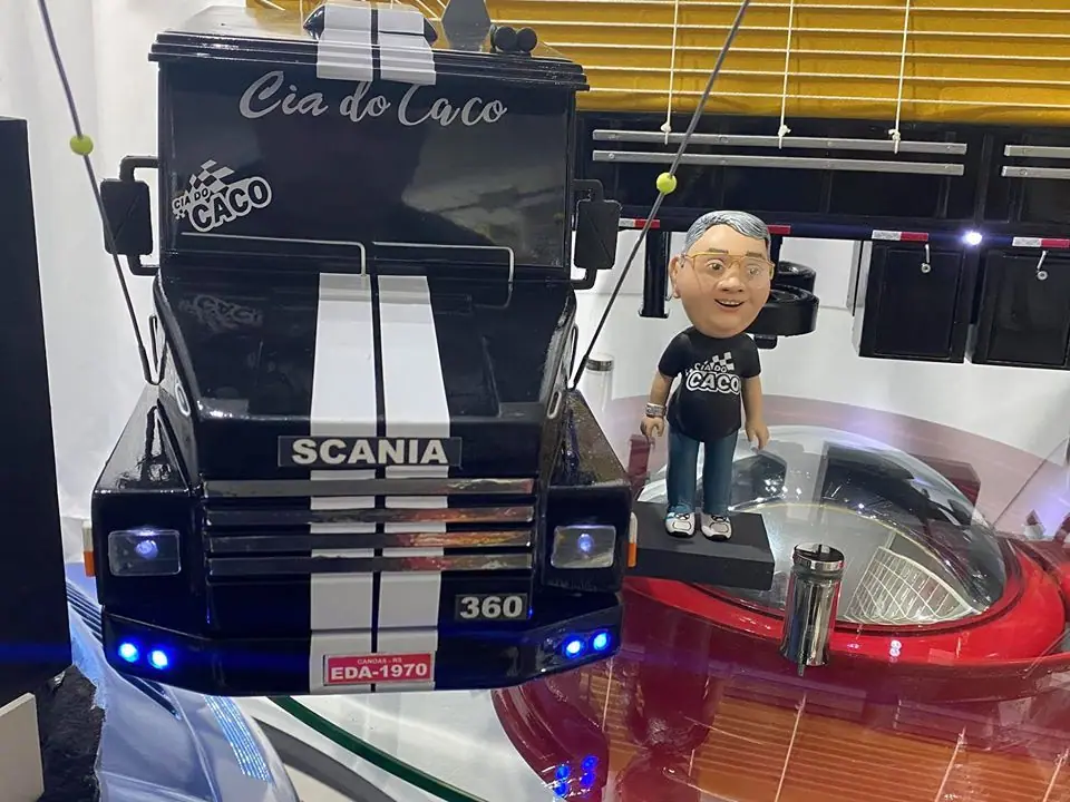 Miniatura de caminhão Scania preto com faixas brancas e um boneco sobre a cabine