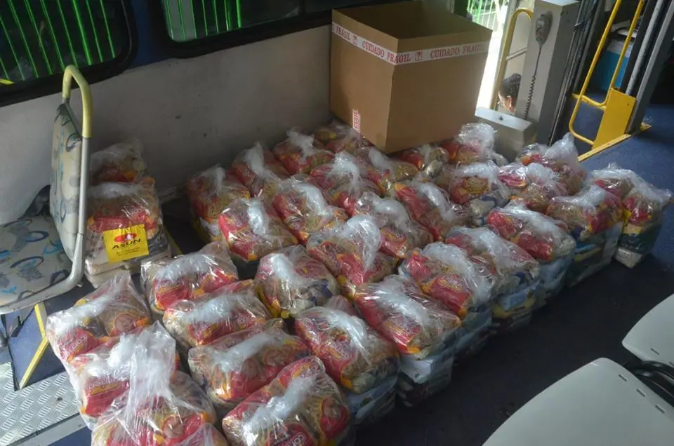 Sacolas de doação empilhadas no piso de um ônibus