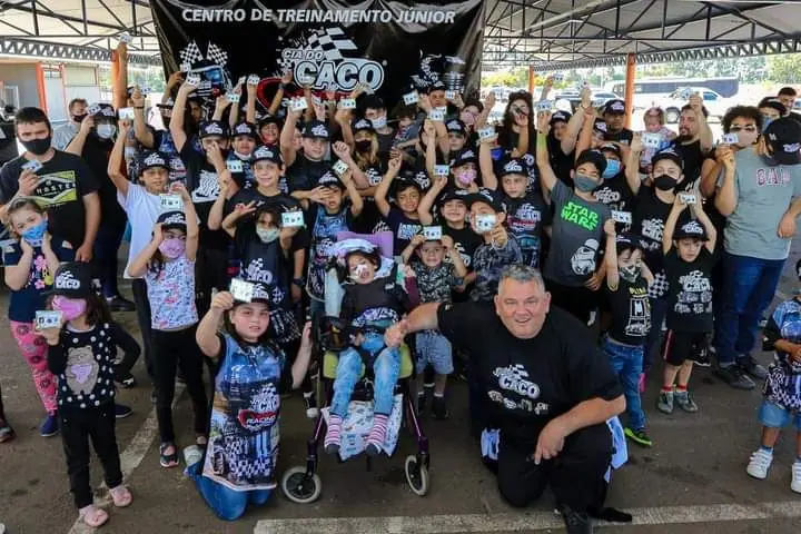 Grupo numeroso de crianças e adultos com camisetas da Cia do Caco posando juntos
