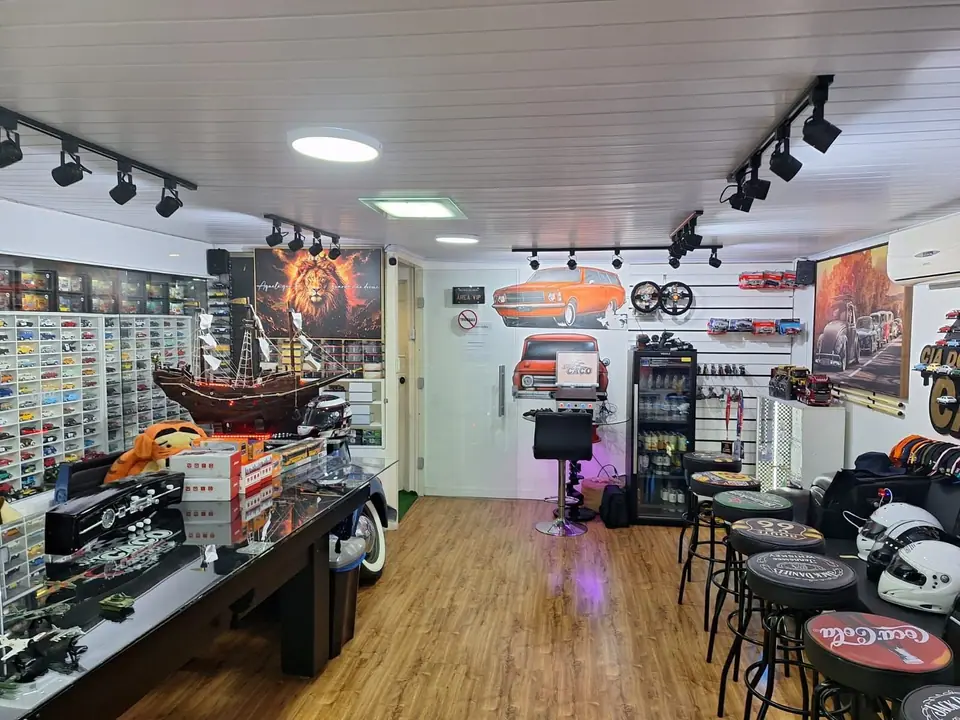 Sala com piso de madeira, vitrines de miniaturas nas paredes e bancos altos