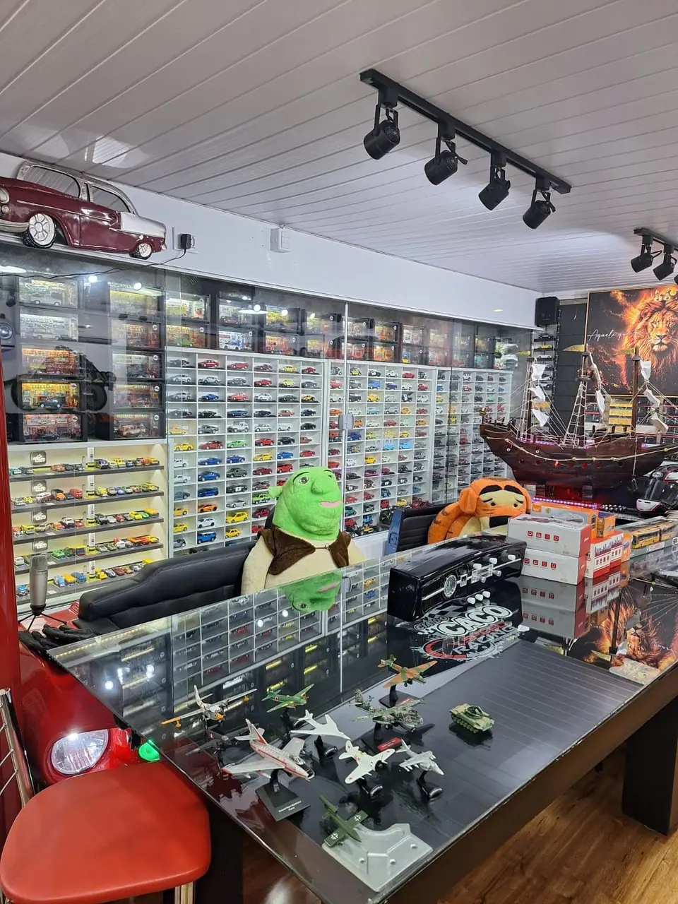 Mesa de vidro com miniaturas diante de paredes cobertas de vitrines
