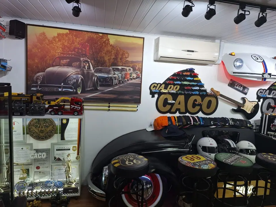 Balcão feito com a frente de um carro preto, com bancos altos e o logo da Cia do Caco na parede
